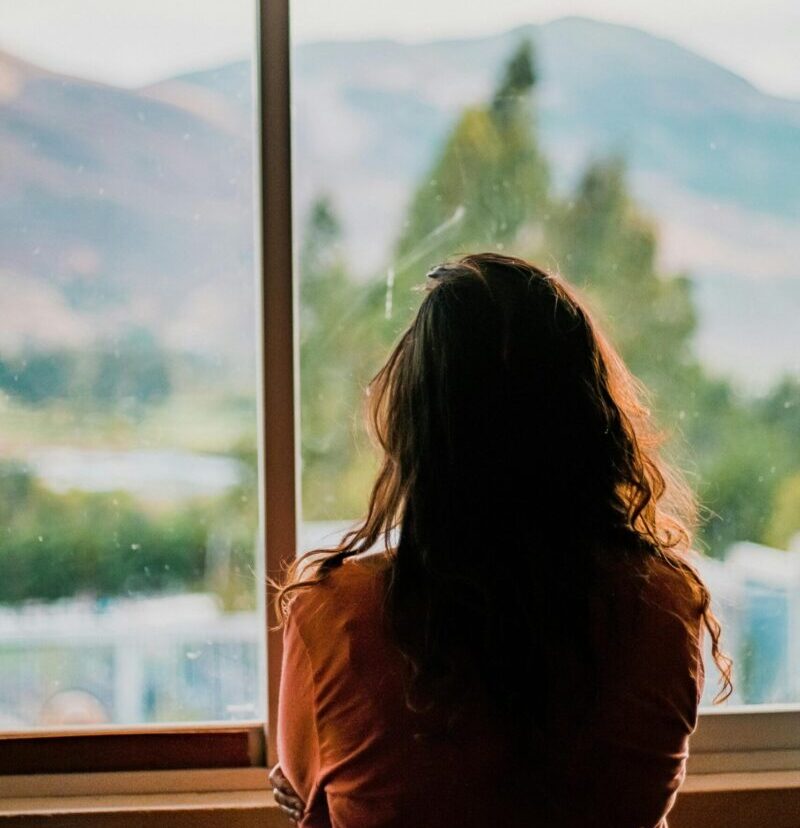 Silhouette of a woman looking out a window at a scenic mountain view in Cajamarca, Peru.