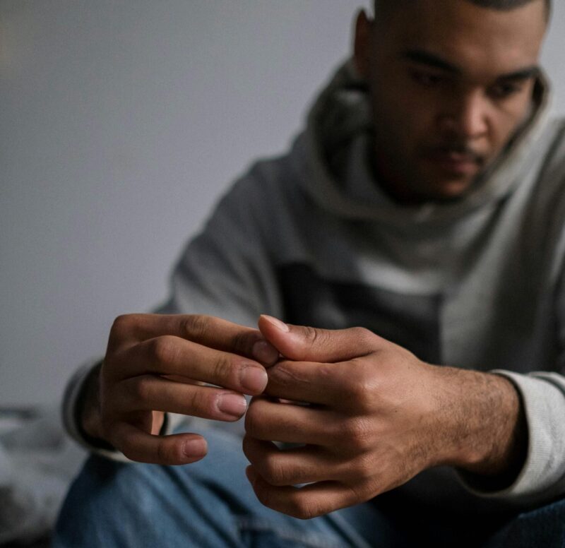 A man sitting indoors looks deep in thought, highlighting themes of mental health and introspection.